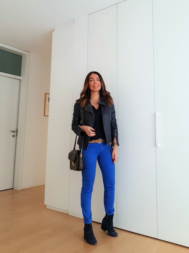 Pochette Métis outfit: pantaloni blu cobalto e blusa blu scura. Giacca in pelle blu.